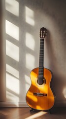 Fototapeta premium An acoustic guitar leaning against a wall, with natural light casting shadows and a neutral background
