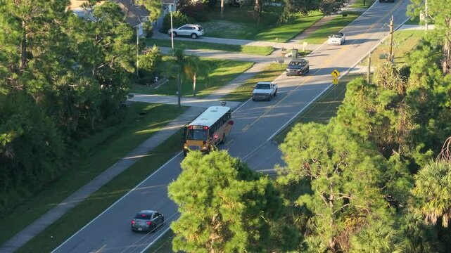 School bus picking up children for their lessons on suburban street bus stop. Public transportation in the USA.