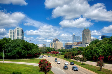 A Raleigh, North Carolina cityscape on a nice day with blue sky and puffy clouds in HDR.