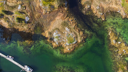 Aerial top down view low tide at Madeira Park, Sunshine Coast, British Columbia. Exposed rocky  land and a dock walkway runs along side 