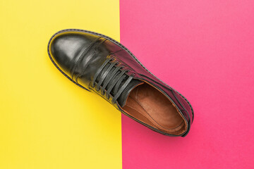 A black shoe on a beautiful yellow background.