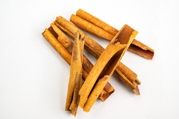 A pile of cinnamon sticks on a white surface