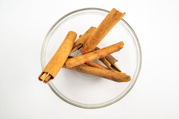 A bowl of cinnamon sticks sits on a white background