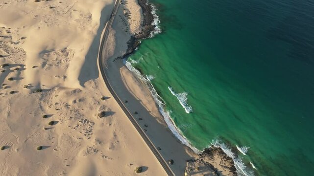 Aerial view of beautiful sand dunes and tranquil ocean with a scenic shoreline, Parque Natural de Corralejo, Fuerteventura, Spain.