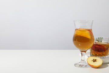 Glasses with apple cider and apple pieces on white background, space for text
