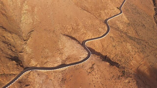 Aerial view of winding road through beautiful arid desert landscape with rugged mountains, Vega de Rio Palmas, Fuerteventura, Spain.
