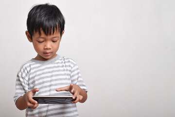 Asian boy with serious face playing smartphone isolated on white background. little boy addicted to playing games. Gaming and Technology concept, copy space