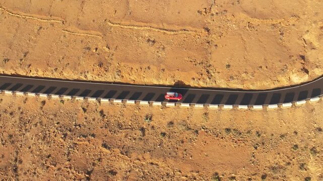 Aerial view of winding road through rocky desert landscape with vehicles, Vega de Rio Palmas, Fuerteventura, Spain.