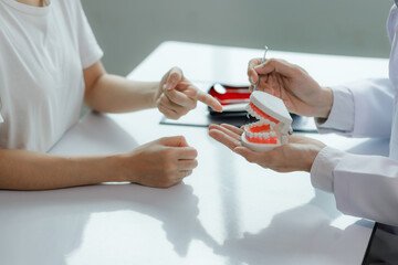 A dentist advises a patient on dental care in a modern clinic, explaining oral hygiene and...