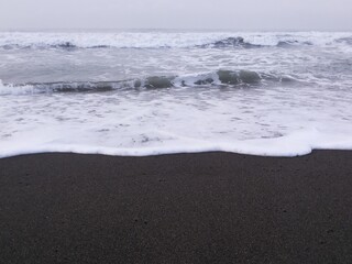 Crashing waves and black sand on Goa Cemara beach.