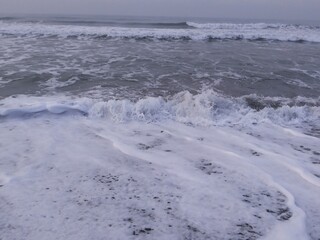 Crashing waves and black sand on Goa Cemara beach.