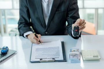 A car salesman in the middle of offering a vehicle and signing a contract.