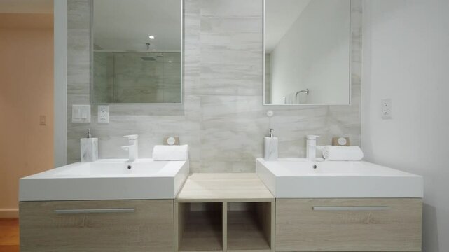 Convenient bathroom vanity with double sink, large mirror and wall-mounted faucets. Minimalist design of bath with light wood tones and clean lines