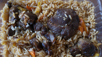 Takeaway meal of rice and meatballs in plastic container. Ready-to-eat dish, convenience food concept. Middle Eastern cuisine pilaf or plov.