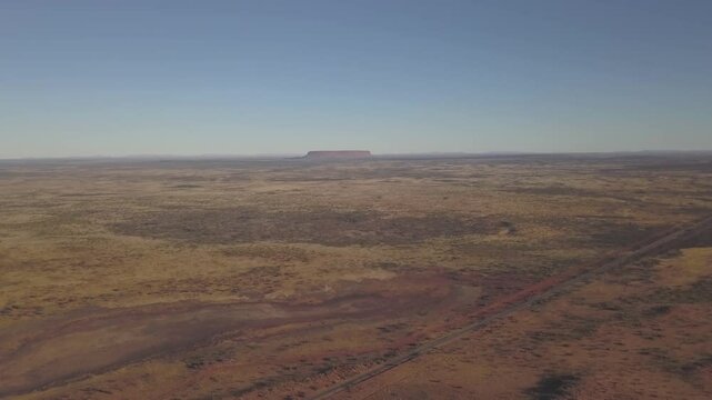 Aerial view of the expansive desert landscape featuring Mount Conner under a clear sky, Imanpa, Australia.