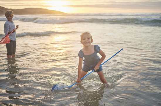 Portrait, sea and smile of girl with net for fishing outdoor in summer on holiday, travel or vacation. Beach, ocean and sunshine with happy child having fun in water for hobby or leisure activity