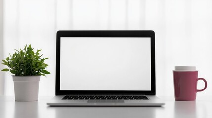 Fototapeta premium Laptop with a blank screen on a bright white desk, accompanied by a small potted plant and a white coffee cup. Sunlight casts shadows on the wall, creating a warm, inviting atmosphere, ideal for use i