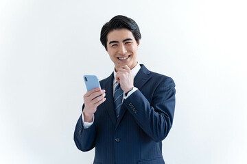 携帯を持ちカメラ目線で悩むスーツを着た日本人男性