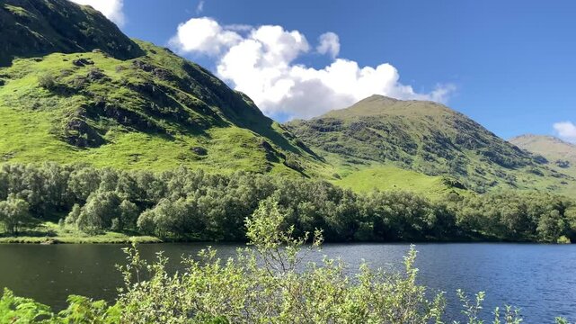 Western highlands Scottish loch on a stunning summer blue sky day with mountains and white clouds