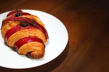 Freshly baked croissants with raspberry jam on a white plate on a wooden table. Healthy eating concept. Organic farm products for breakfast or lunch.
