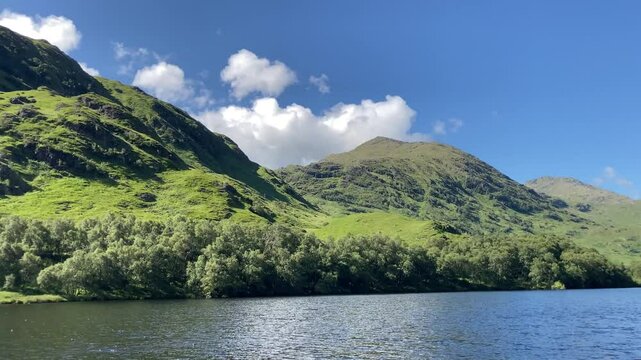 Western highlands Scottish loch on a stunning summer blue sky day with mountains and white clouds