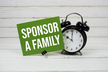 Sponsor A Family text message on paper card with alarm clcok on green background