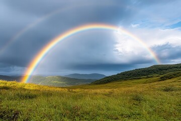 A vibrant rainbow arches over a lush green landscape under partly cloudy skies, creating a picturesque natural scene.
