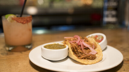 Taco served with two sauces with a refreshing drink on the side