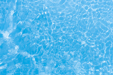 Blue water with ripples on the surface. Defocus blurred transparent blue colored clear calm water surface texture with splashes and bubbles. Water waves with shining pattern texture background.