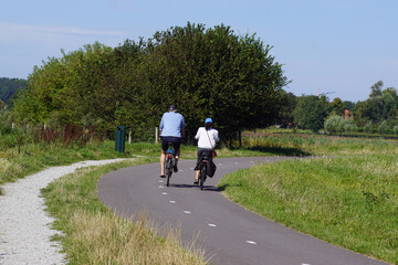 Naklejka premium Cyclists on the cycle path (called Paddenpad) next to a shell walking path in the Dutch village of Bergen. Meadows, forest. Summer, August, Netherlands
