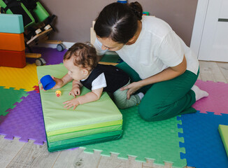 Boy with muscle weakness wearing spine corset engages in rehab exercises with a therapist, using...