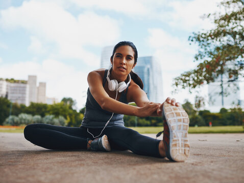 Woman, fitness and stretching legs outdoor in city for healthy body, flexible and exercise for wellness. Sports, start and runner warm up muscle to prepare for workout, training or marathon on road