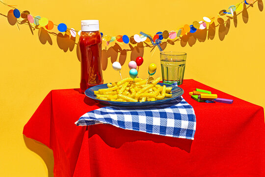 Still life of birthday decoration with french fries and ketchup on table against yellow background