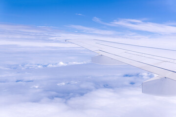 view from airplane window during flight, wing and cloudscape, view above clouds