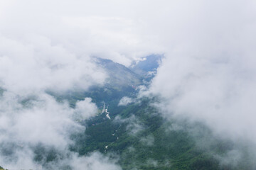 aerial view of wild forested mountain slope through clouds