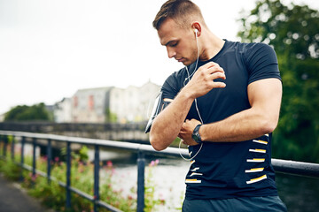 Obraz premium Bridge, man and outdoor with smartphone or earphones for music playlist and streaming service in Germany. Online, internet and jogging for training, fitness and workout with motivational audio