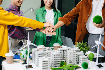Group of diverse multiethnic businesspeople standing neare table looking at model of building from residential project. Green business company