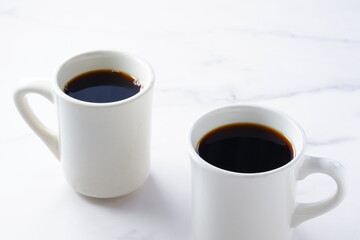 淹れたてのコーヒーが入ったふたつのマグカップで、二人が打ち合わせをしているイメージ
