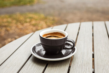 A cup of black coffee on the table of a cafe or bakery terrace