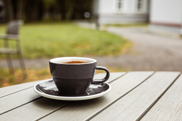 A cup of black coffee on the table of a cafe or bakery terrace