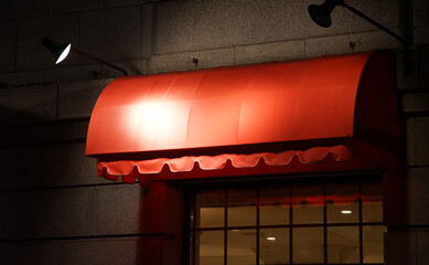 Red tent roof at the entrance illuminated by the lighting of the restaurant building at night