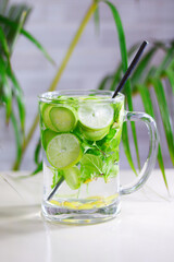Detox water with cucumber, lemon, ginger, and mint in a glass on a white background