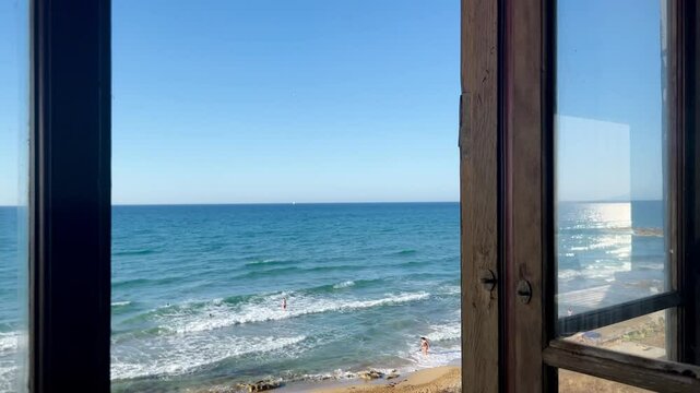 A beautiful view over a blue sea and the beach from an open window