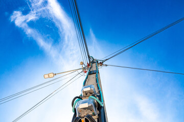 electric poles with bright blue sky and white clouds in background, electric pole thailand