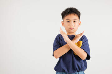 Portrait Asian young kid boy unhappy or confident standing holding two cross arms say no X sign,...