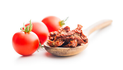 Sun dried red tomatoes on wooden spoon isolated on white background.
