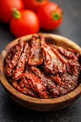 Sun dried red tomatoes in bowl on black table.