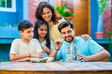 Indian family making eco-friendly Ganesh idol in outdoor garden for Ganesh Chaturthi celebration
