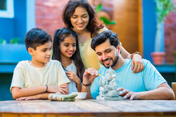 Indian family making eco-friendly Ganesh idol in outdoor garden for Ganesh Chaturthi celebration