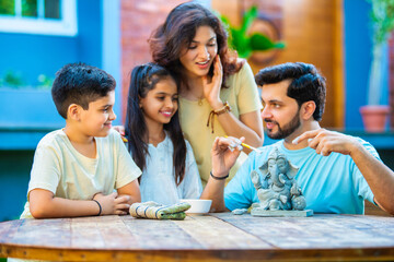 Indian family making eco-friendly Ganesh idol in outdoor garden for Ganesh Chaturthi celebration